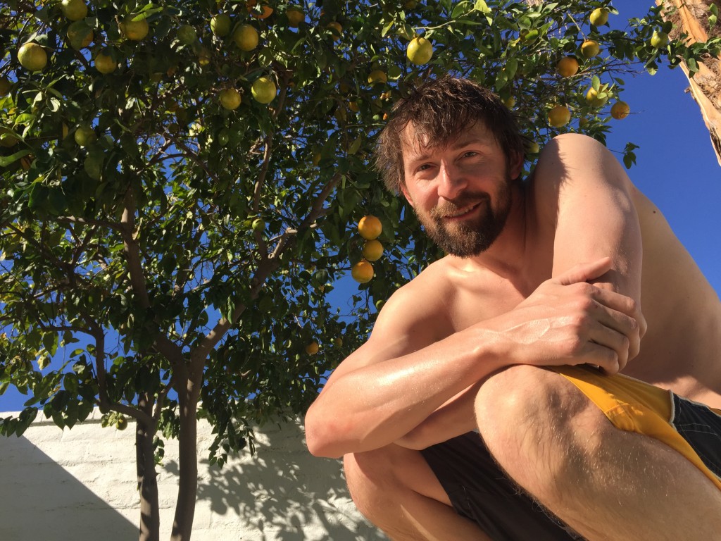 Jeff sits crouched under an orange tree.