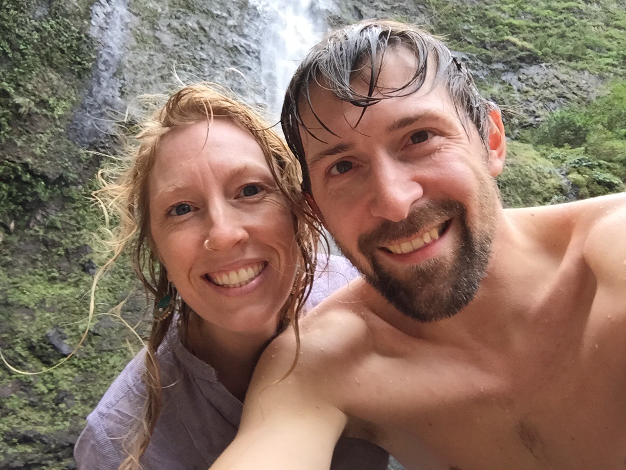 Andrea and Jeff in a selfie with the falls and green covered walls behind them.